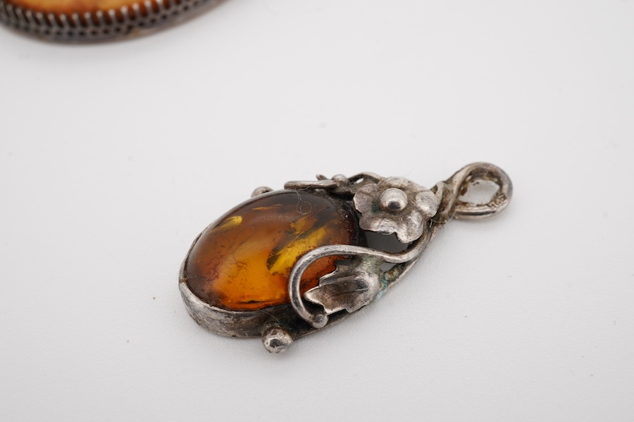 An Indian white metal fringe necklace, 37.5cm, a large antique white metal mounted amber pendant(a.f.), one other later smaller amber pendant and a filigree brooch. Condition - poor to fair